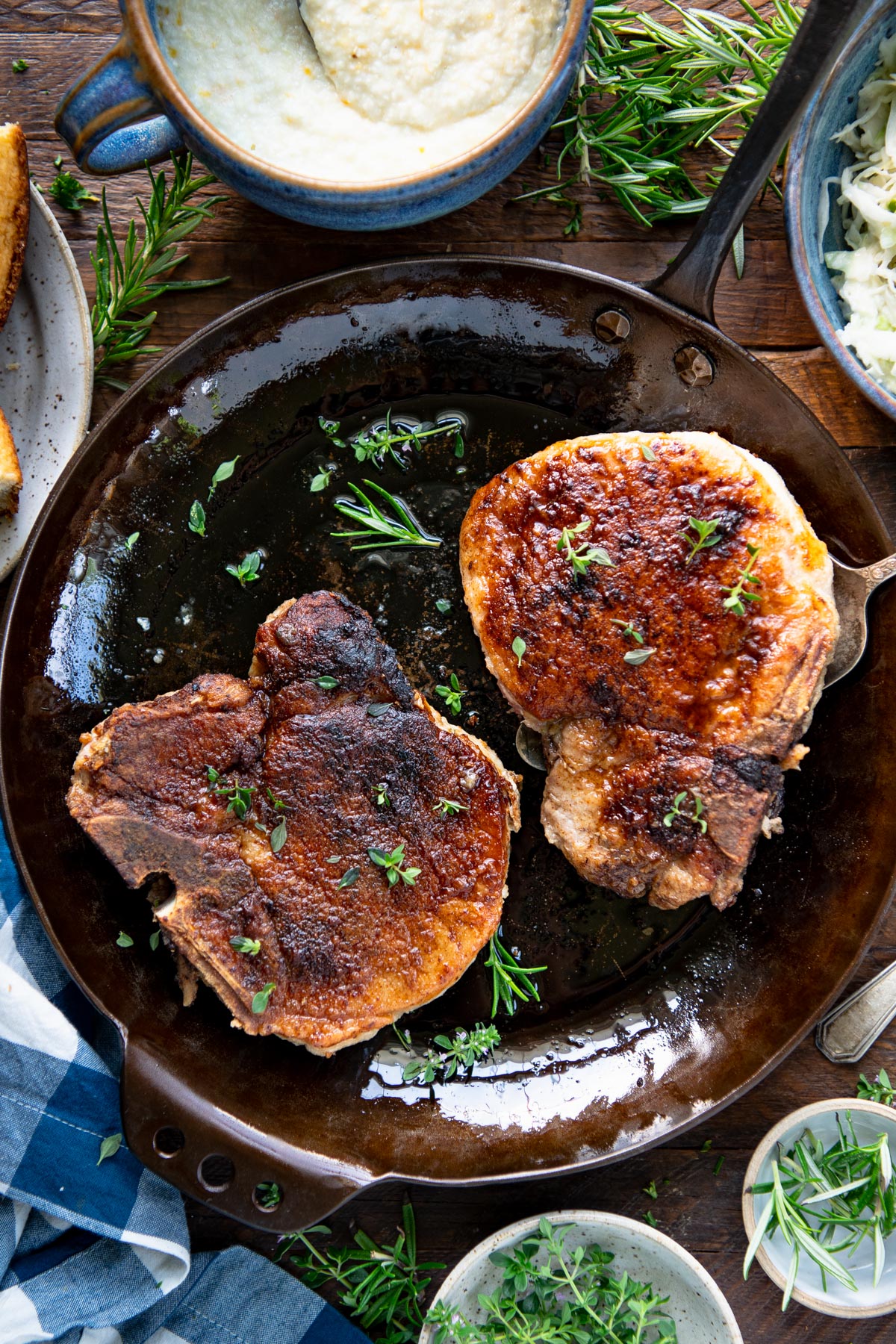 Skillet of Creole pork chops with fresh herbs for garnish.