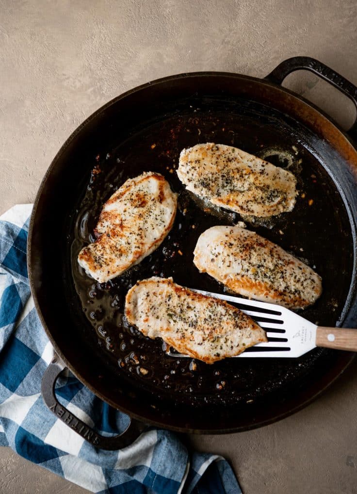 Browning chicken breast in a cast iron skillet.