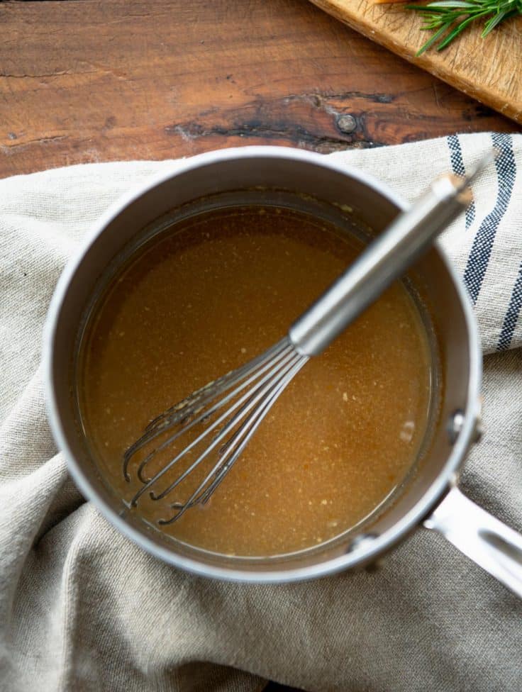 Cider dijon sauce in a saucepan with a whisk.