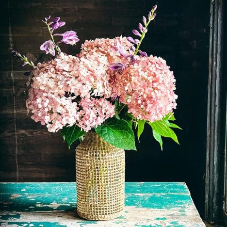 Square side shot of a vase of pink hydrangeas.