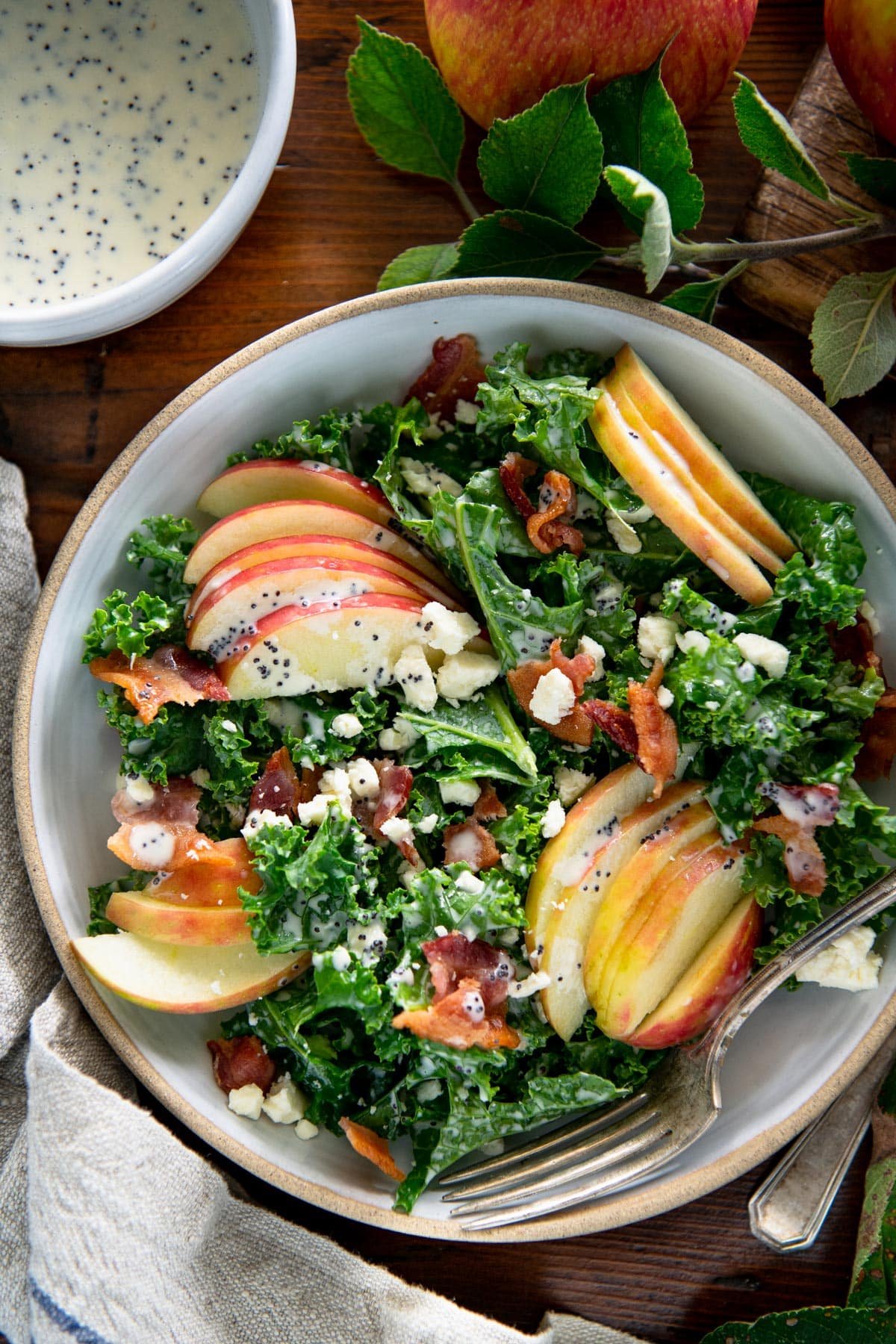Close overhead shot of kale apple salad in a white bowl.