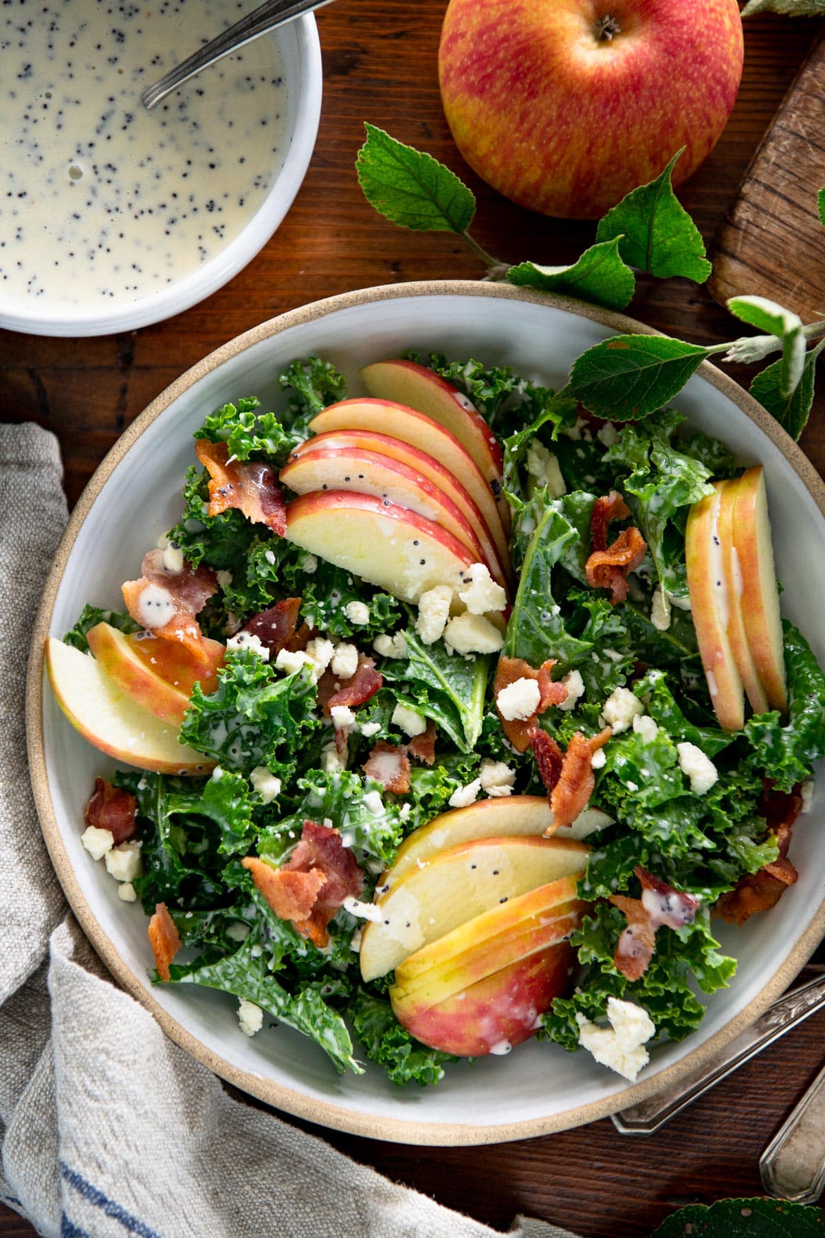 Close overhead shot of a bowl of kale salad with apple and poppy seed dressing.