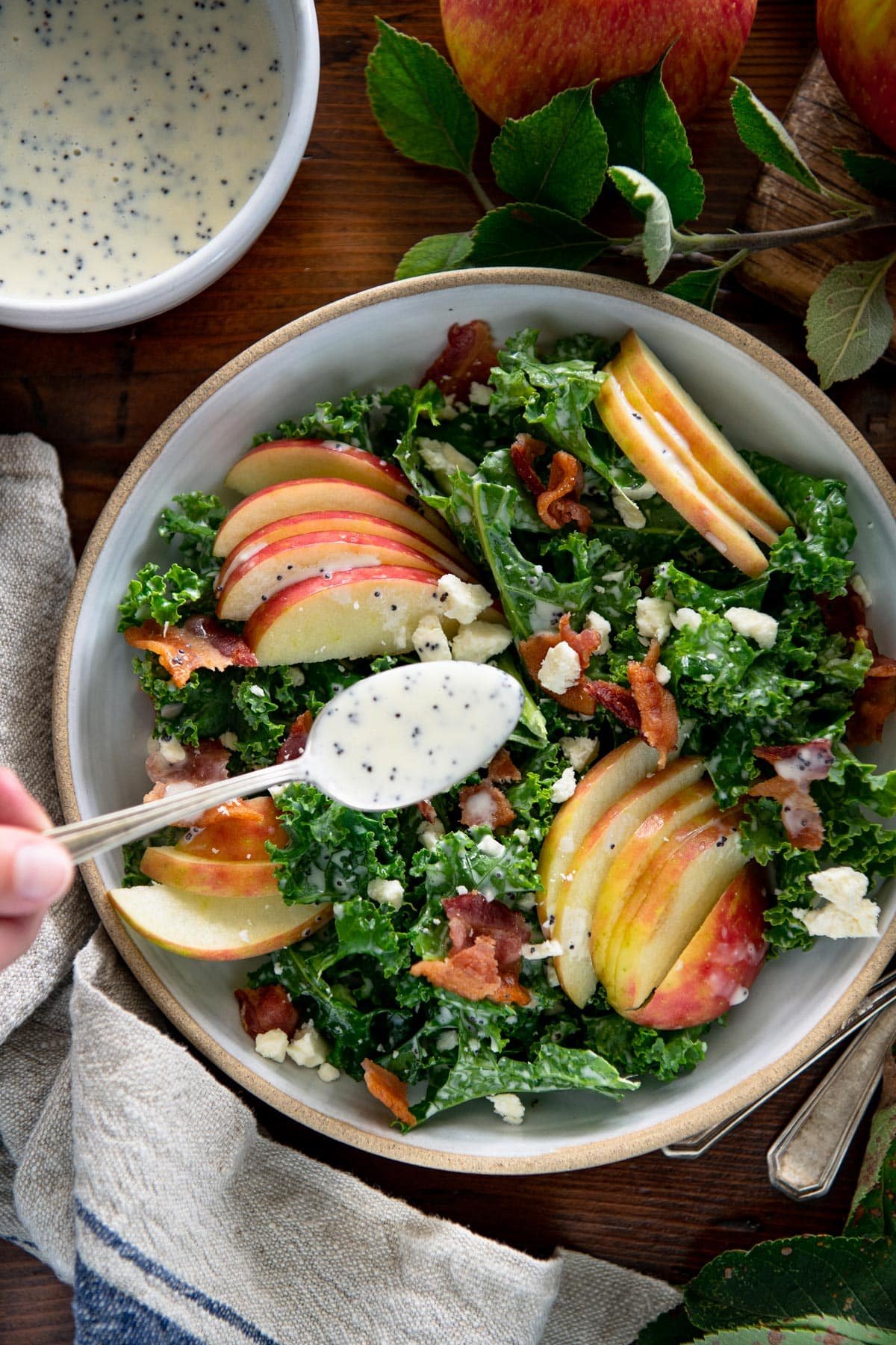 Hand dressing kale apple salad with creamy poppy seed dressing.