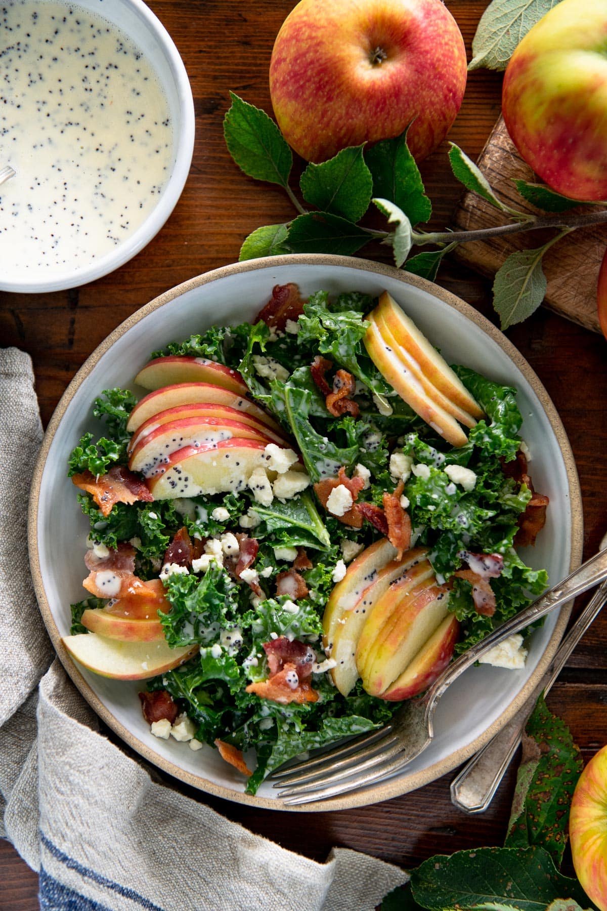 Overhead image of a kale salad with apples on a wooden table.