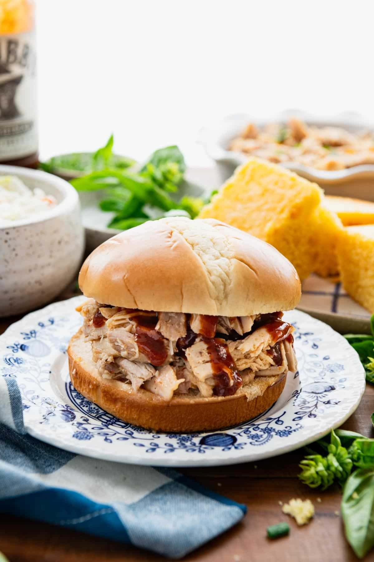 Close up front shot of crock pot pulled chicken on a sandwich bun with bbq sauce.