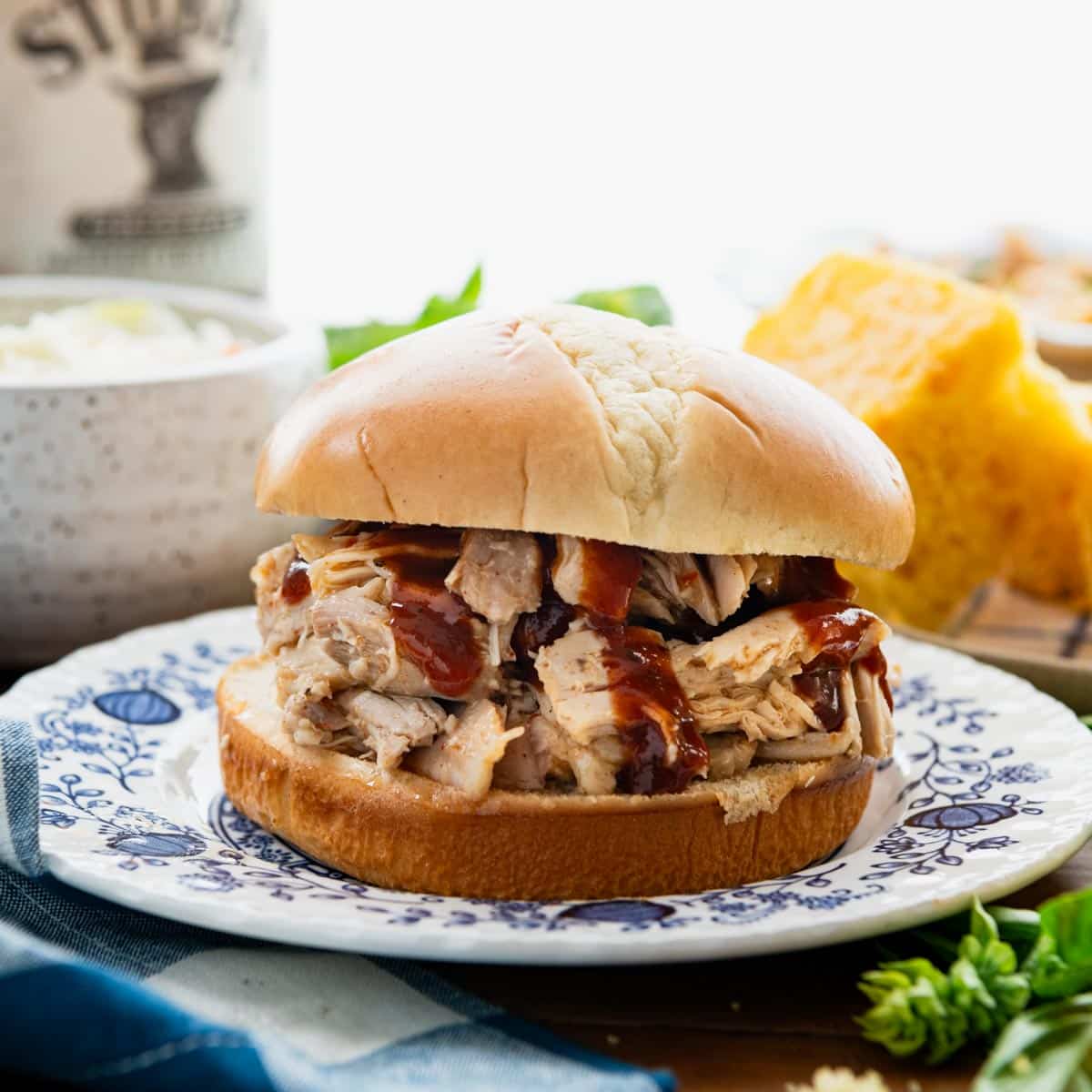 Square side shot of slow cooker shredded chicken on a bun with barbecue sauce.