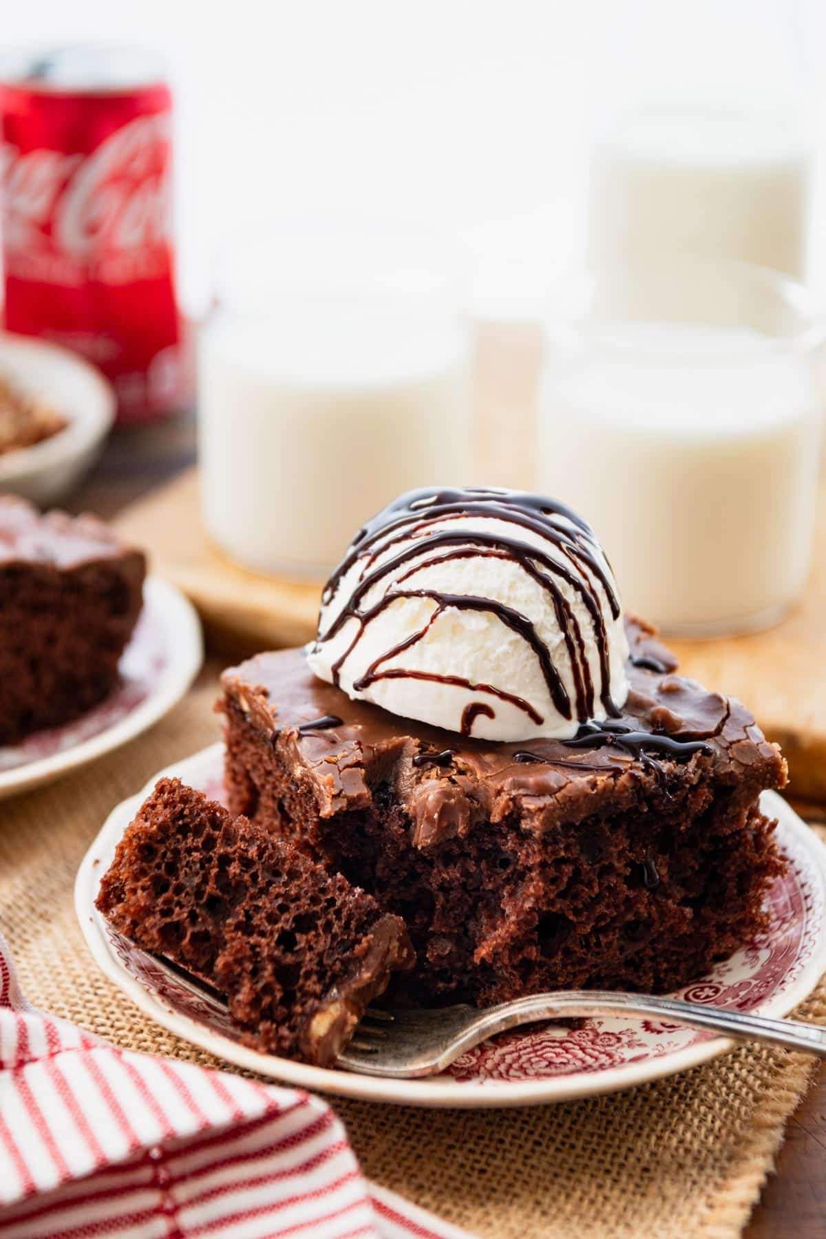 Side shot of southern coca cola chocolate cake on a plate with milk in the background.