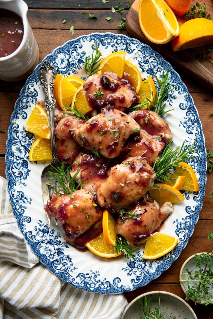 Overhead shot of cranberry chicken on a blue and white serving platter.