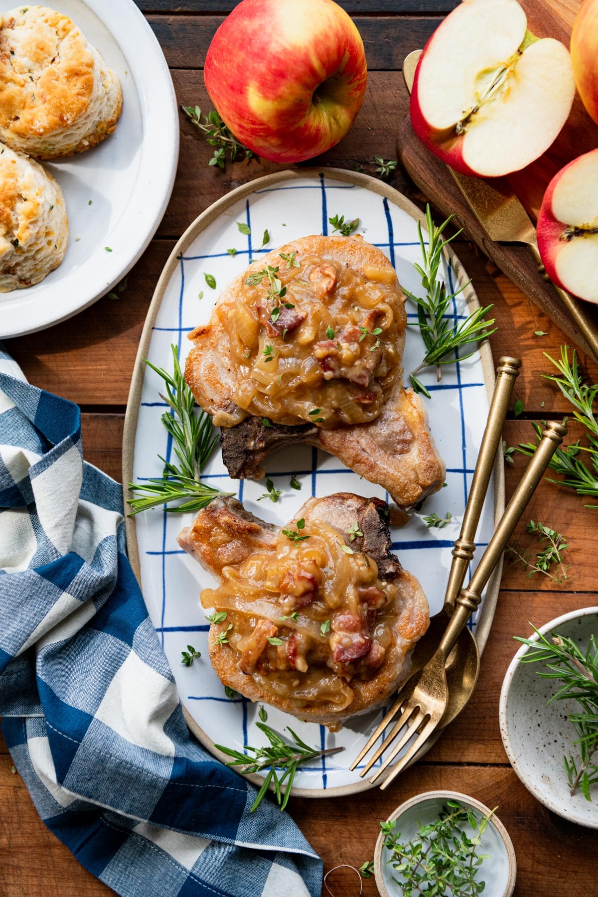 Crock Pot Southern smothered pork chops on a serving tray with a side of biscuits and apples.