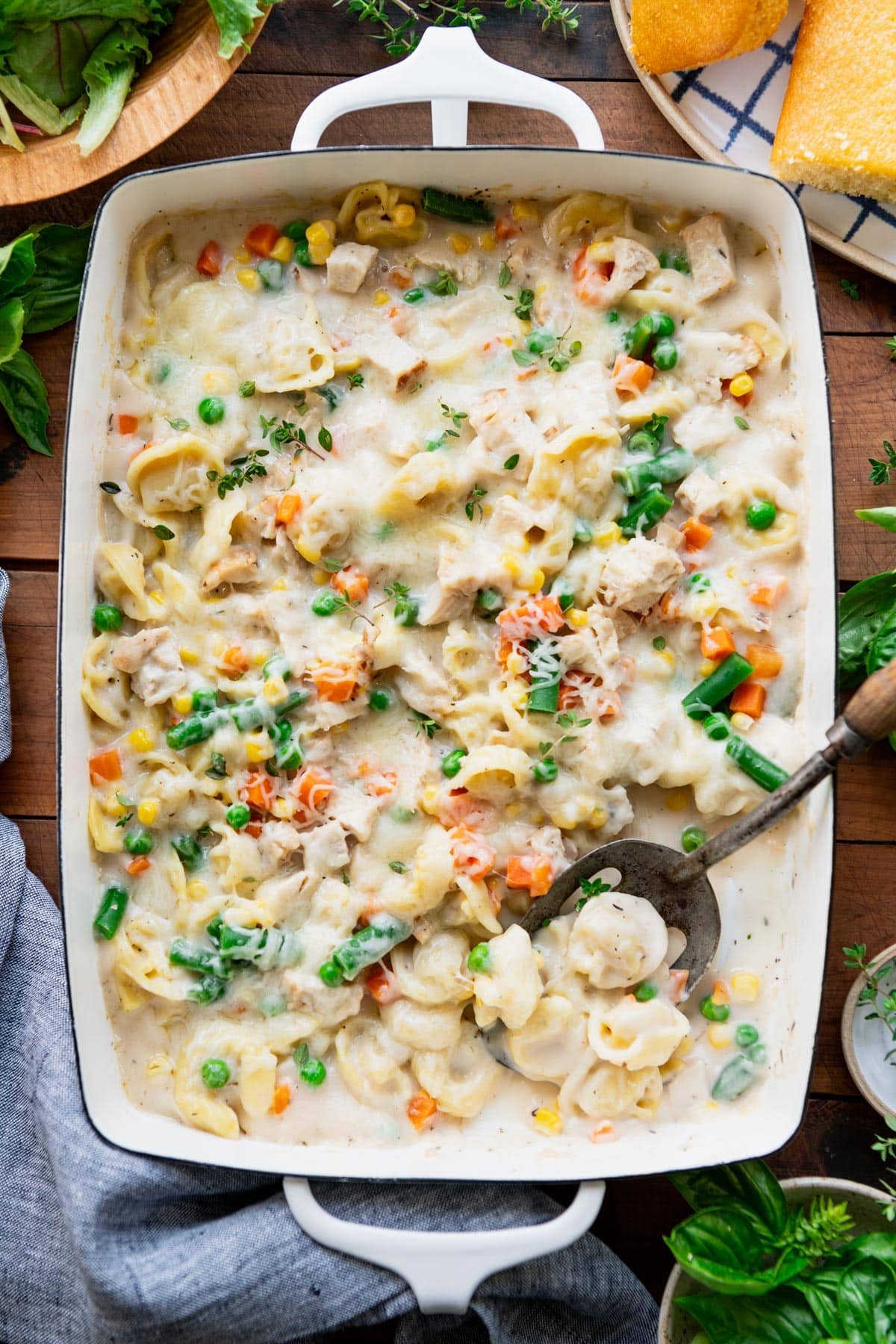 Baked tortellini alfredo in a white dish with a serving spoon.