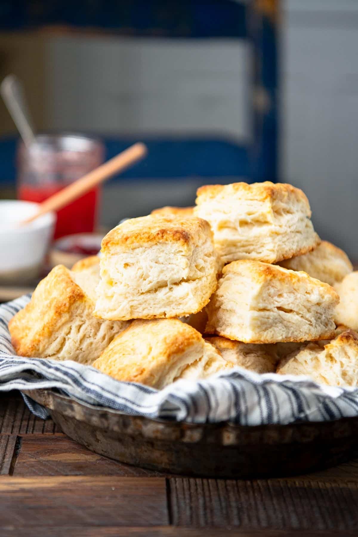 Close up side shot of a bowl of buttermilk flaky biscuits on a wooden table.