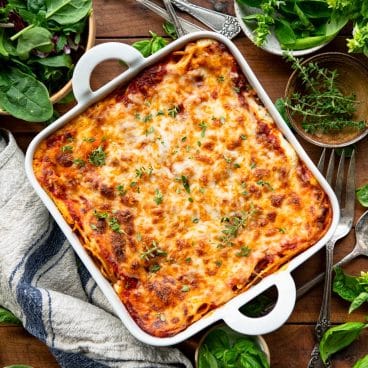 Square overhead shot of a pan of million dollar baked spaghetti on a wooden table.