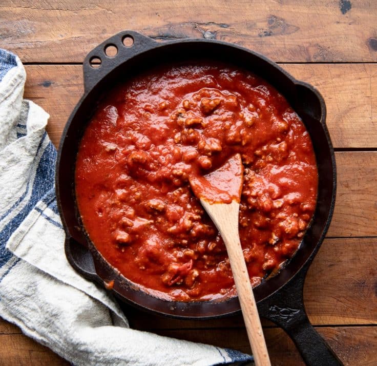 Ground beef and marinara sauce in a cast iron skillet.