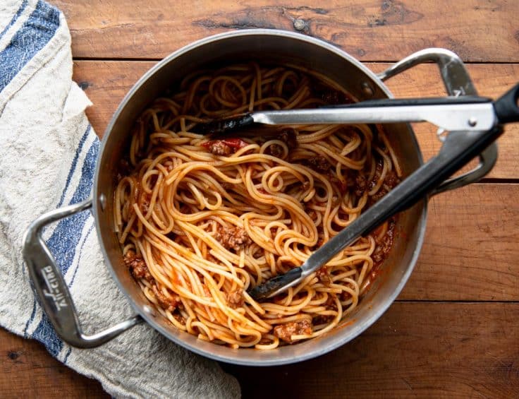 Spaghetti noodles with meat sauce in a pot.