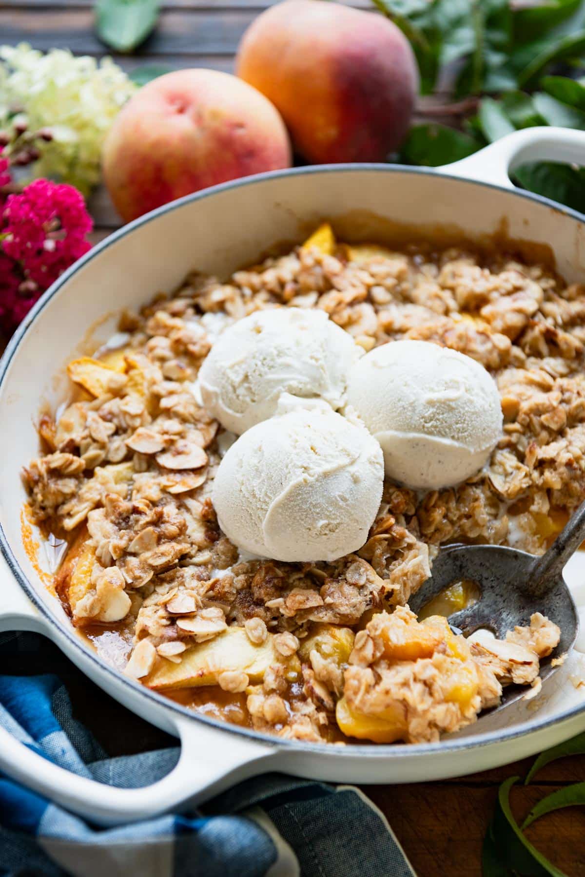 Close up side shot of a serving spoon in a skillet of peach crisp.