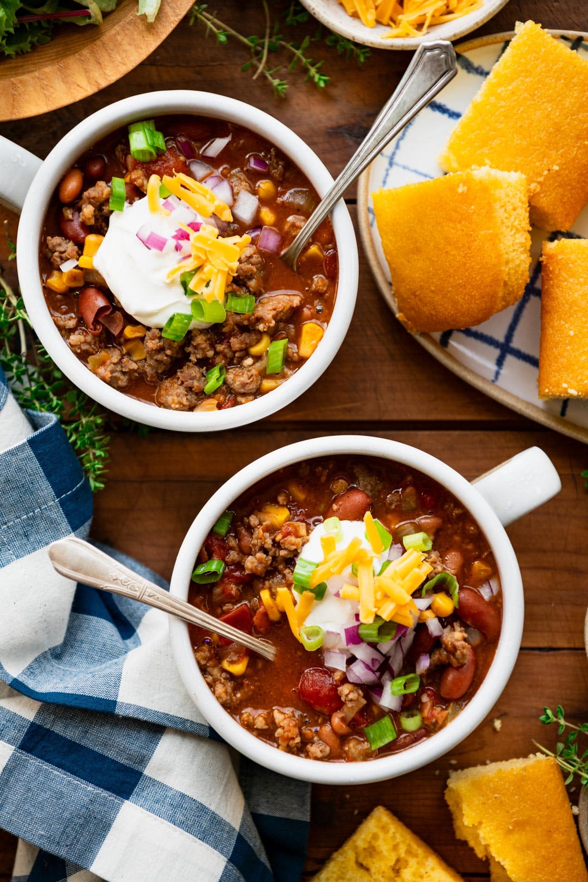 Overhead image of two bowls of the best pork chili recipe on a wooden table.