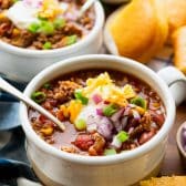 Close up side shot of two bowls of pork chili on a dinner table.