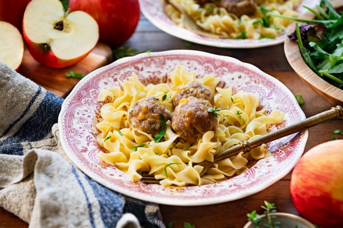 Horizontal shot of a bowl of pork meatballs with apples and cheddar cheese.