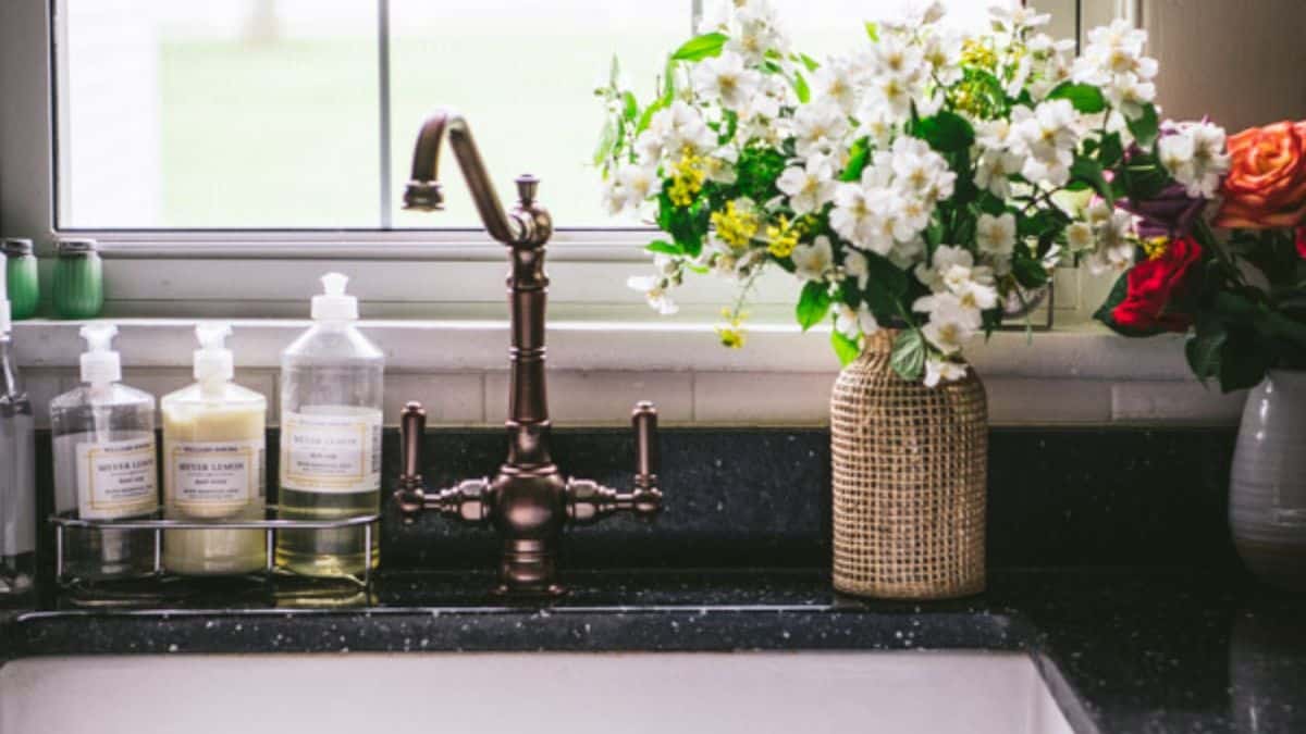 A vase of flowers by the kitchen sink 