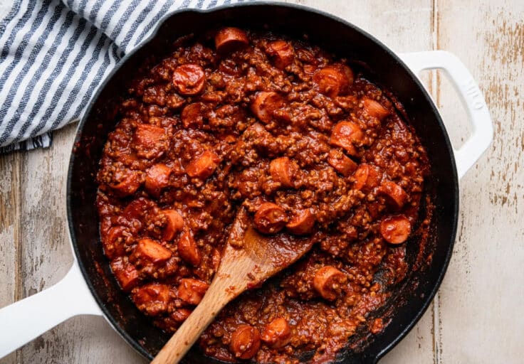 Cooking the filling for a chili dog casserole in a cast iron pan.