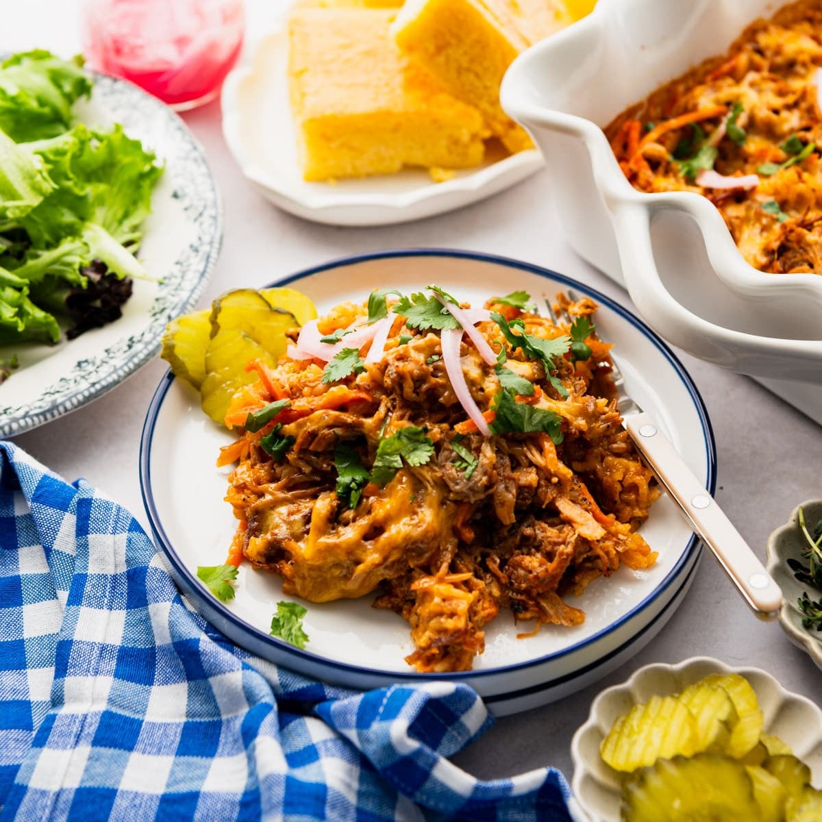 Square side shot of pulled pork casserole on a dinner table.