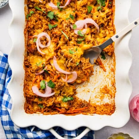 Square overhead shot of a bbq pulled pork casserole in a white baking dish.