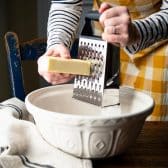 Grating butter into a large bowl.