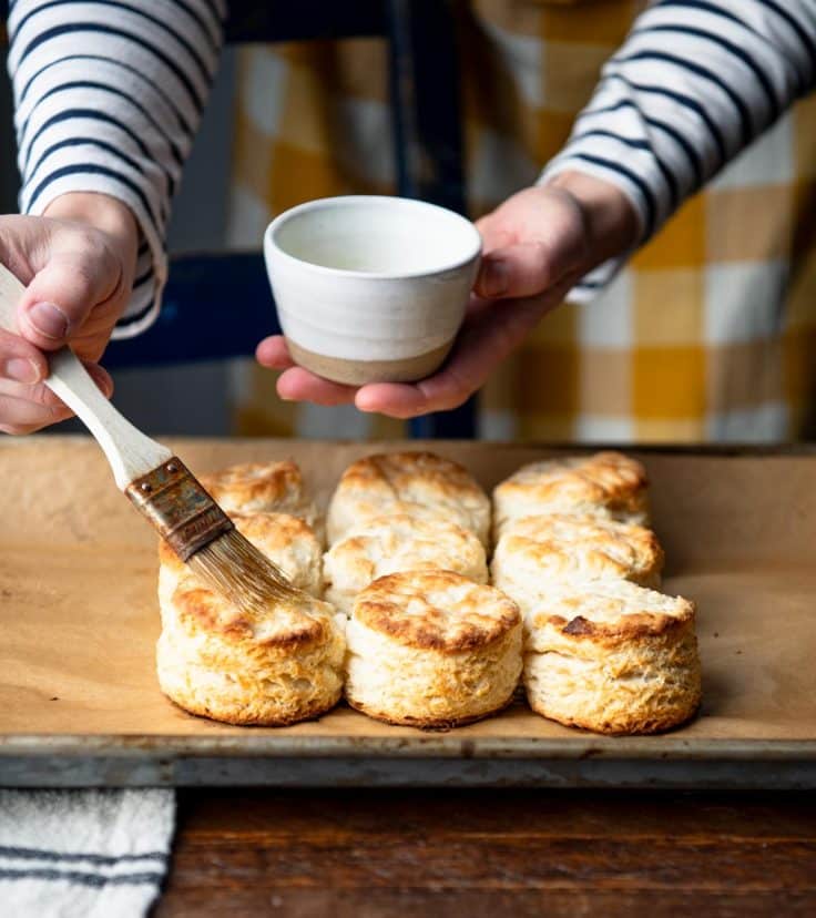 Brushing 3 ingredient biscuits with melted butter.