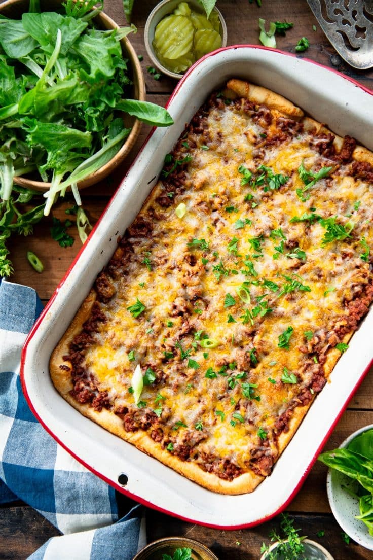 Overhead shot of a sloppy joe casserole with a side salad on a table.