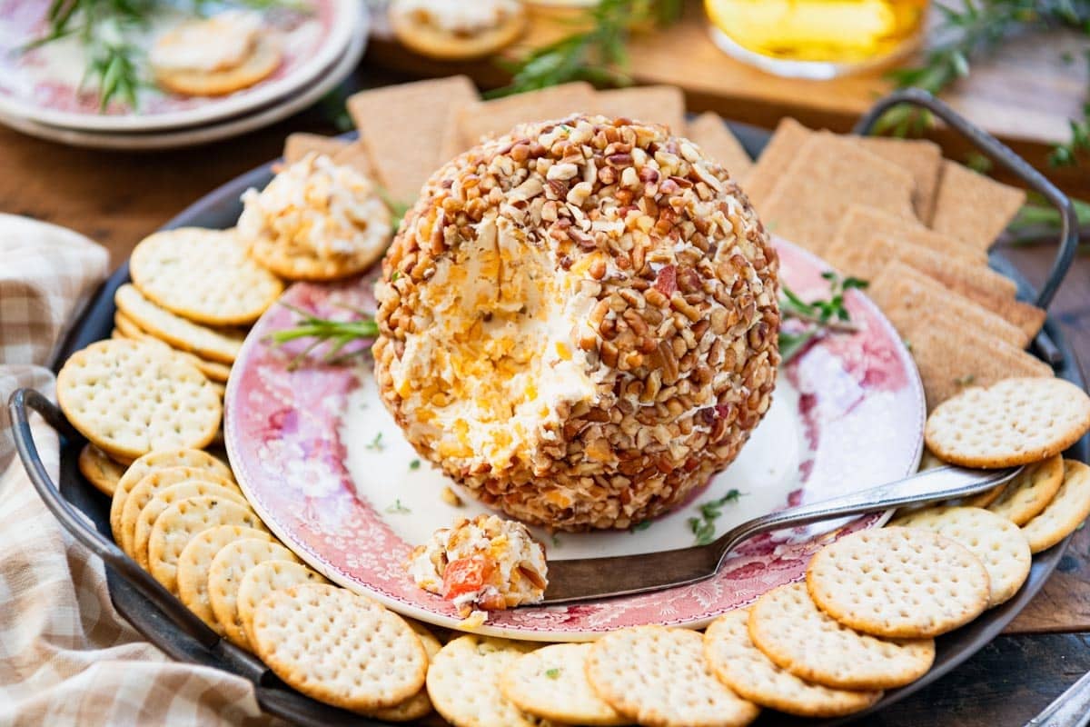 Horizontal image of a platter with an easy cheese ball recipe and crackers on the side.