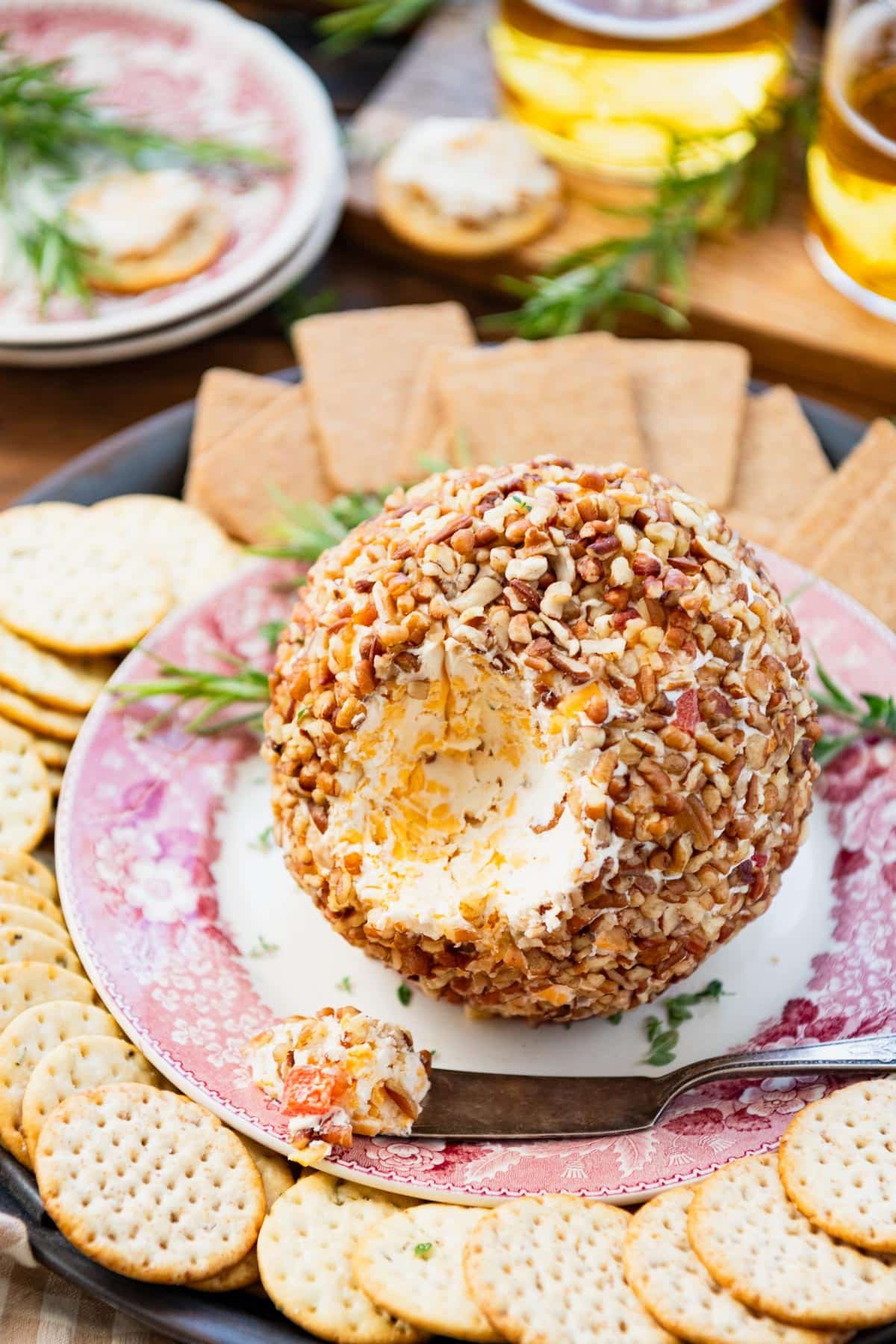 Red and white serving platter with a cheese ball and crackers.