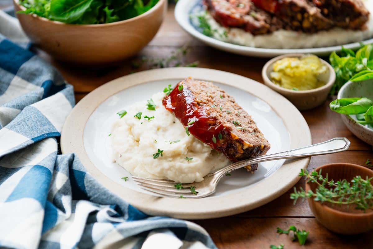 Horizontal shot of a plate of cheeseburger meatloaf with mashed potatoes.