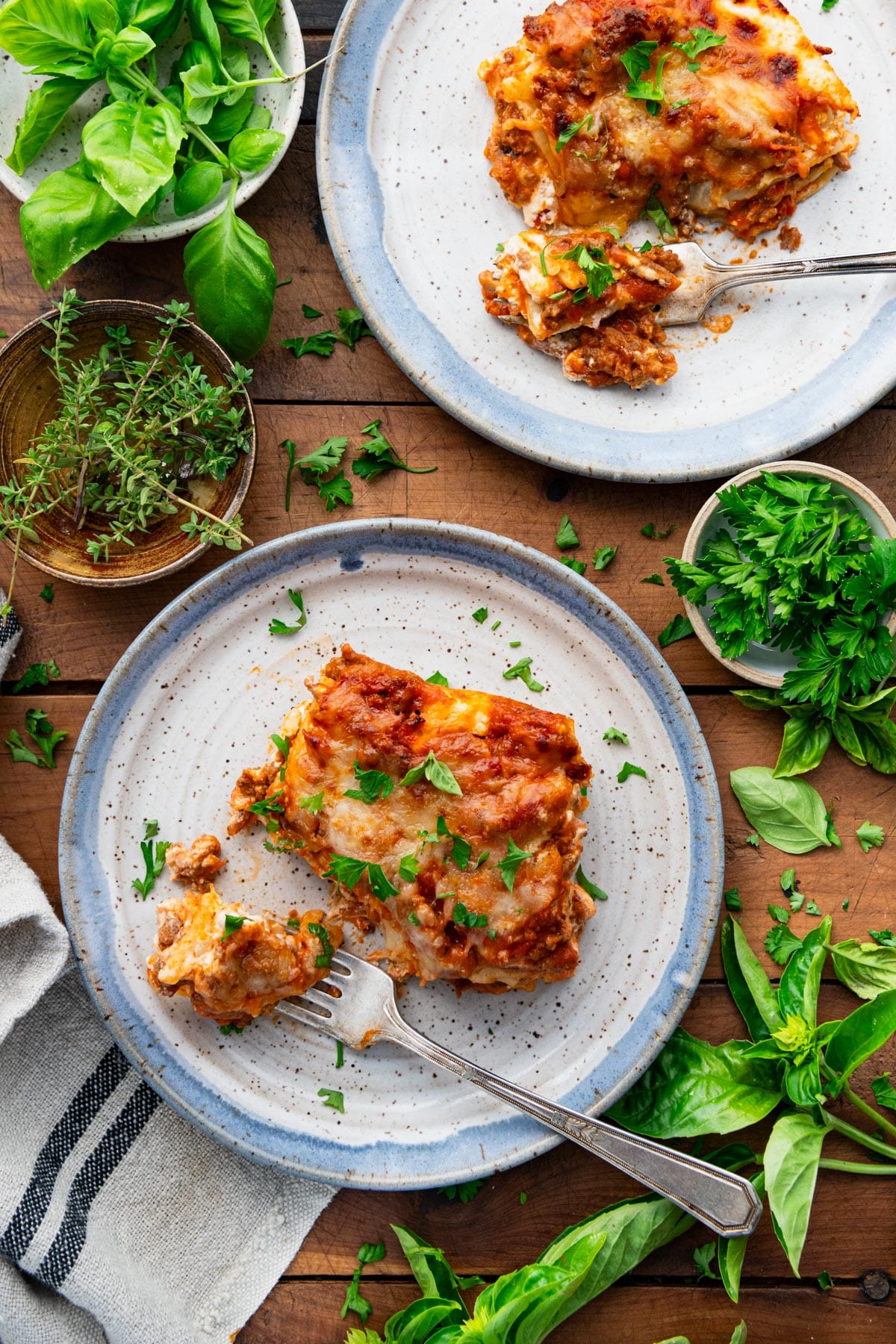 Two plates of classic homemade lasagna recipe on a wooden dinner table.