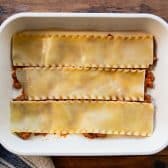 Layering noodles and meat sauce in a pan for lasagna.
