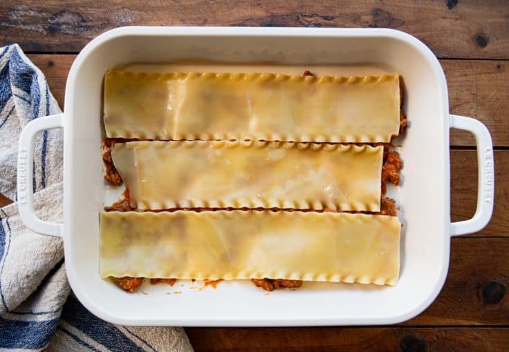 Layering noodles and meat sauce in a pan for lasagna.
