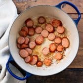 Browning andouille sausage in a pot.