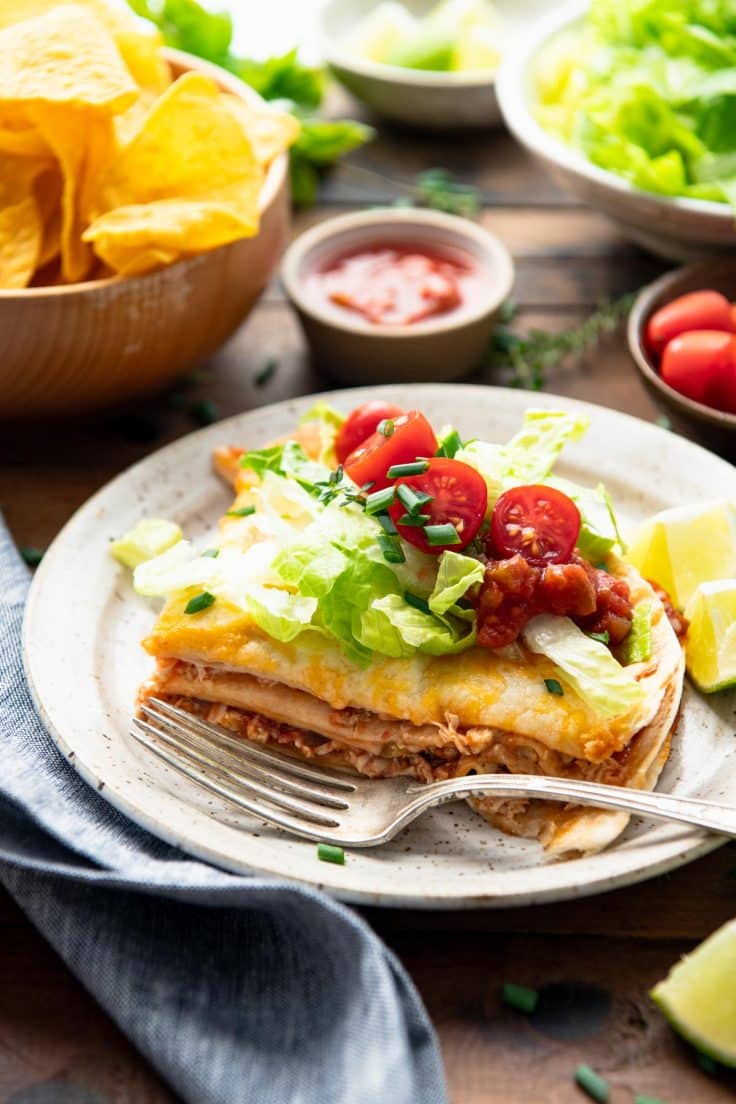 Easy chicken quesadilla casserole served on a plate with salsa, lettuce, and tomatoes.