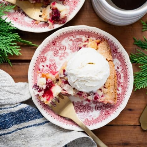 Square overhead image of a gold fork taking a bite of cranberry pie.