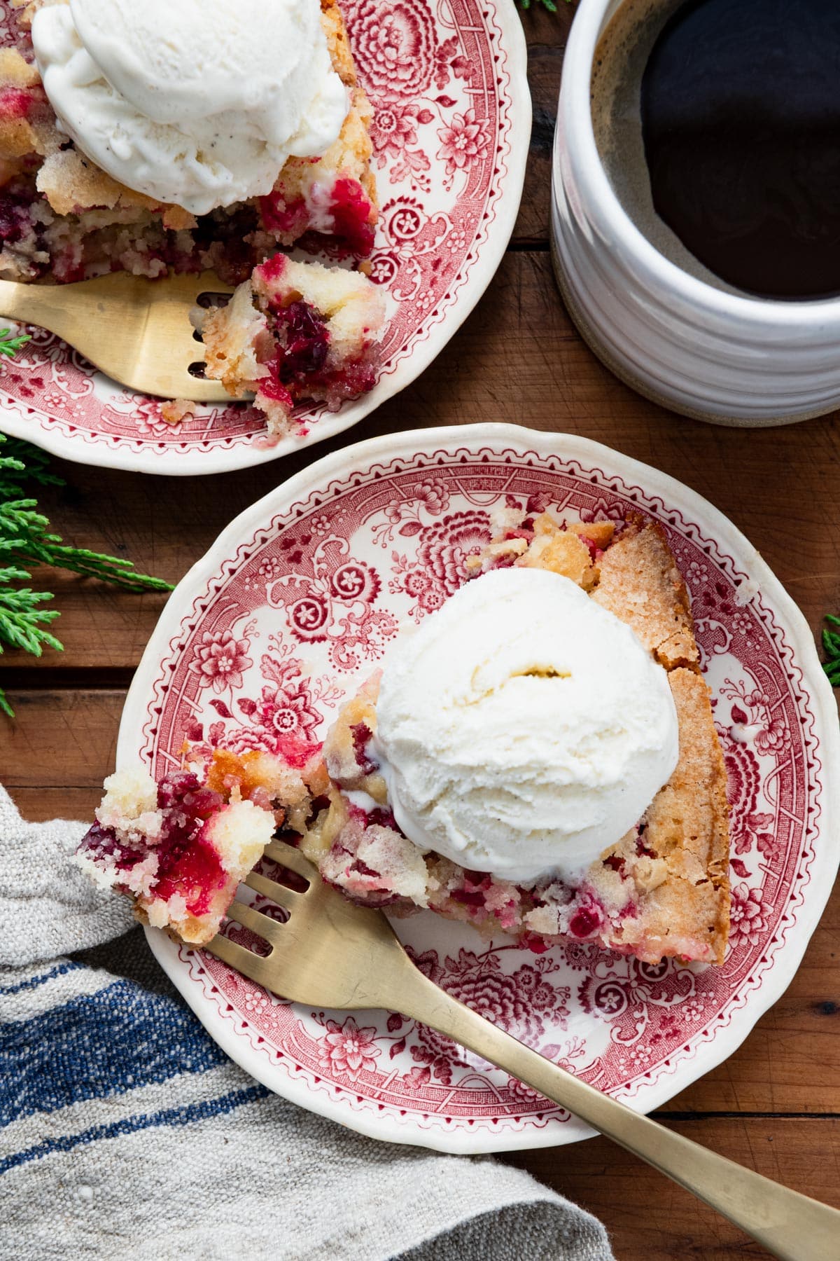 Overhead shot of a slice of cranberry pie on a red and white plate with ice cream.