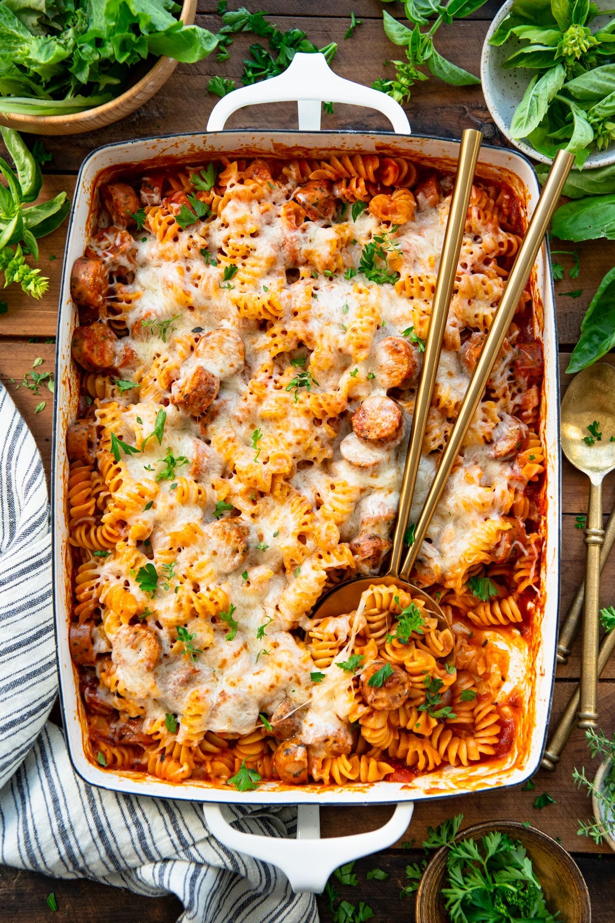 Overhead image of italian sausage pasta bake in a white dish on a wooden table.