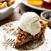 Side shot of pecan chocolate pie on a plate with a scoop of vanilla ice cream.