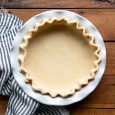 Unbaked pie crust in a white dish.