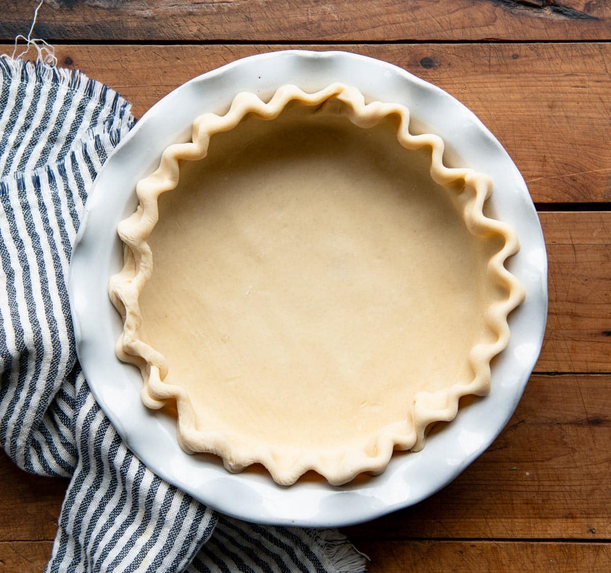 Unbaked pie crust in a white dish.