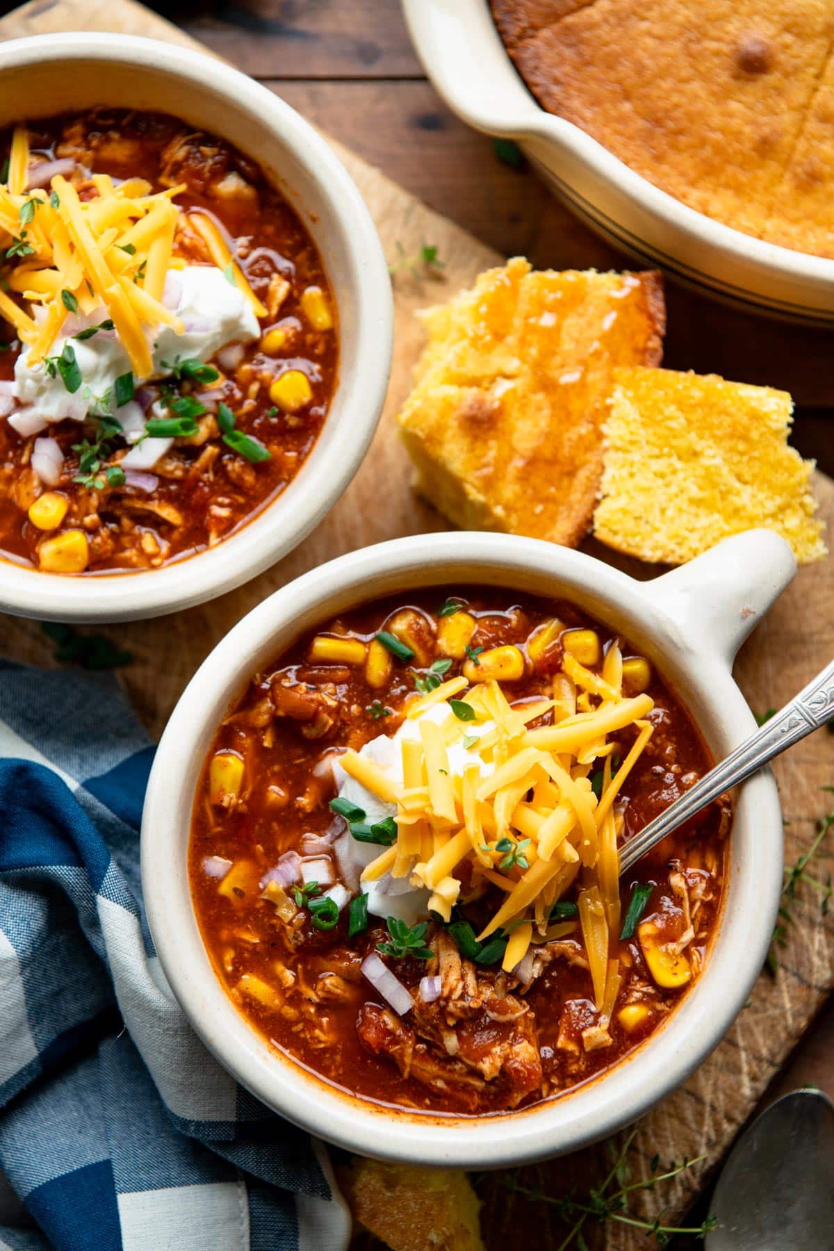 Overhead image of two bowls of leftover turkey chili on a wooden table with a side of cornbread.