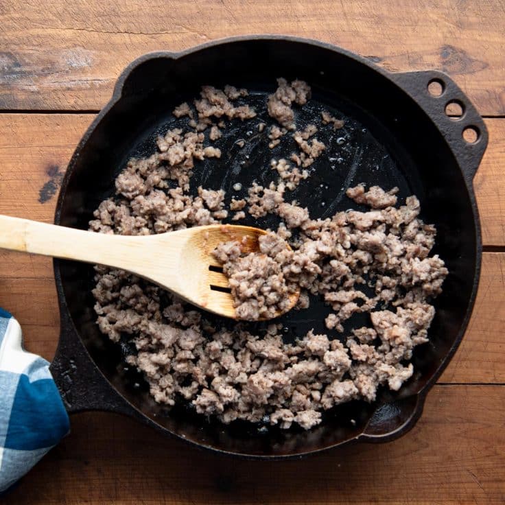 Browning pork sausage in a cast iron skillet.