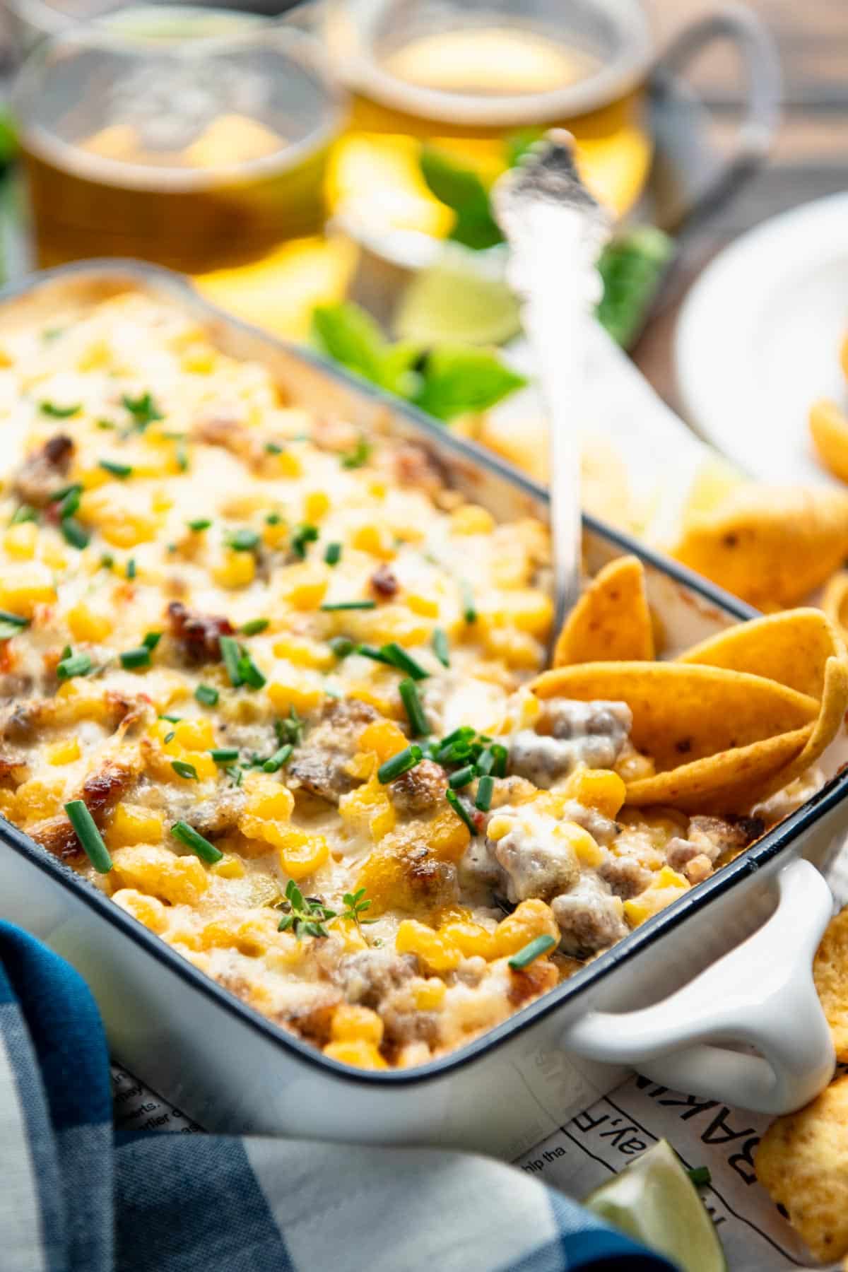Side shot of a dish of sausage dip with corn.