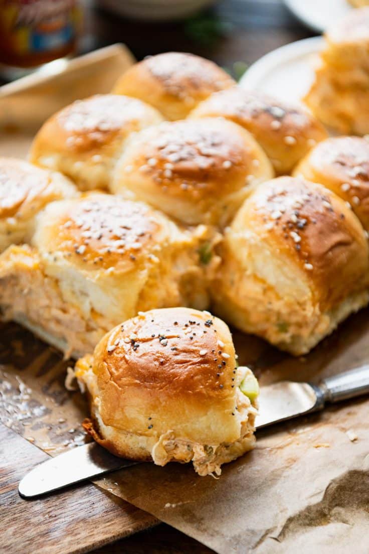 Buttery buffalo chicken dip sliders on a wooden cutting board.