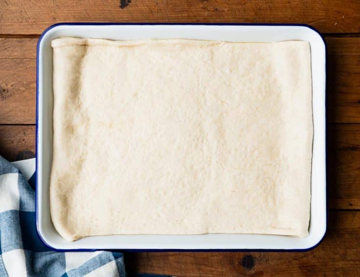 Crescent roll dough unrolled in a pan.