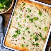 Chicken alfredo crescent roll bake in a pan with fresh herbs on top for garnish.