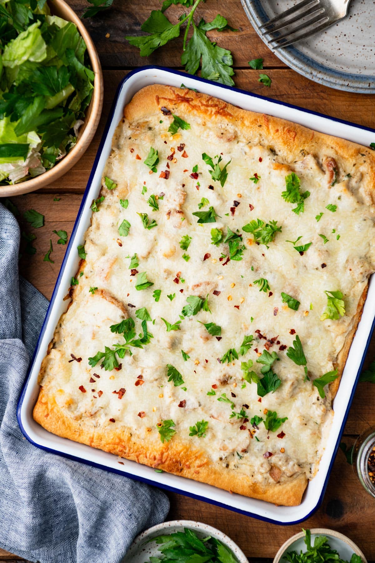 Chicken alfredo crescent roll bake in a pan with fresh herbs on top for garnish.